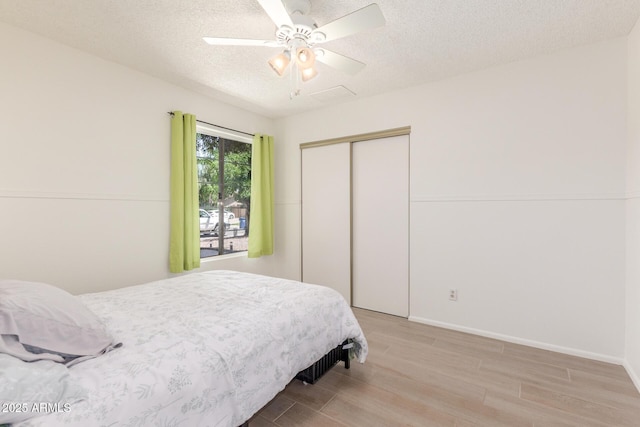 2031 W Gila Ln, Chandler, AZ 85224 - bedroom with light wood-style floors, a textured ceiling, a closet, a ceiling fan, and baseboards