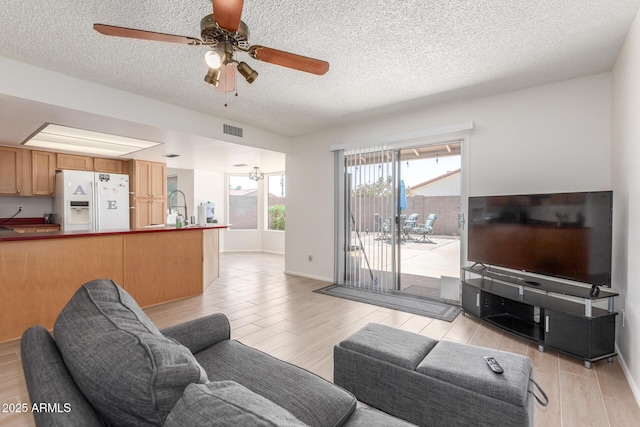 2031 W Gila Ln, Chandler, AZ 85224 - living room featuring light wood finished floors, a ceiling fan, a textured ceiling, and baseboards