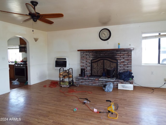 living room with a fireplace, wood-type flooring, heating unit, and ceiling fan