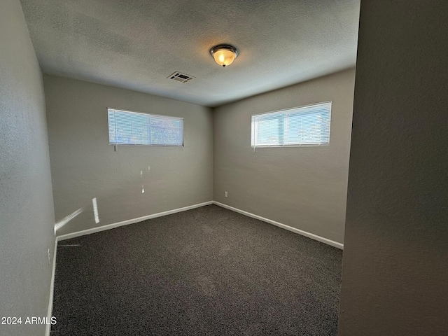 carpeted spare room with a textured ceiling