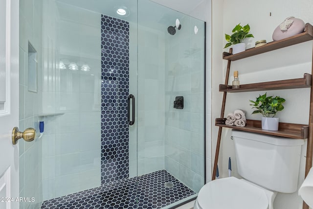 bathroom featuring a shower with door and toilet