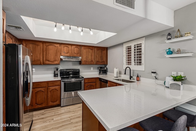 kitchen featuring appliances with stainless steel finishes, sink, kitchen peninsula, a breakfast bar area, and light hardwood / wood-style flooring