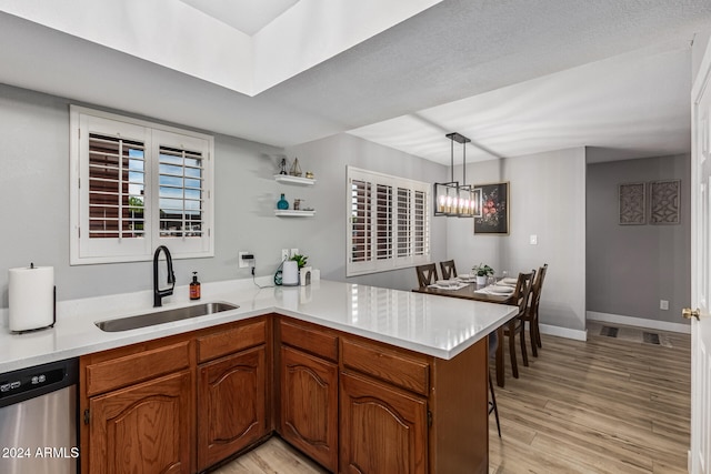 kitchen with dishwasher, hanging light fixtures, kitchen peninsula, sink, and light wood-type flooring