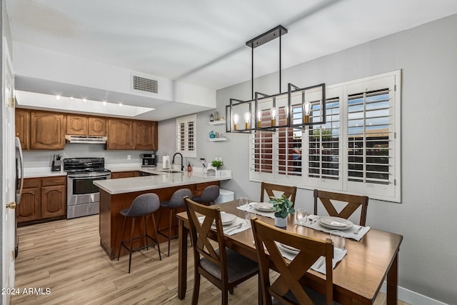 kitchen featuring kitchen peninsula, sink, decorative light fixtures, stainless steel electric range oven, and light hardwood / wood-style floors