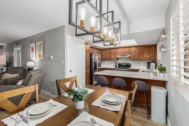 dining area with a notable chandelier, sink, and light wood-type flooring