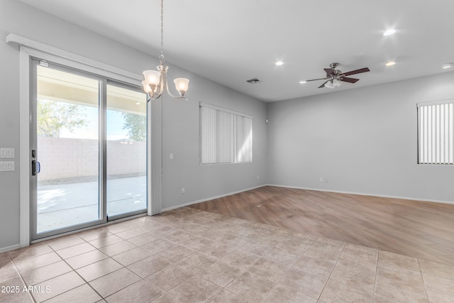 unfurnished room featuring ceiling fan with notable chandelier and light tile patterned floors