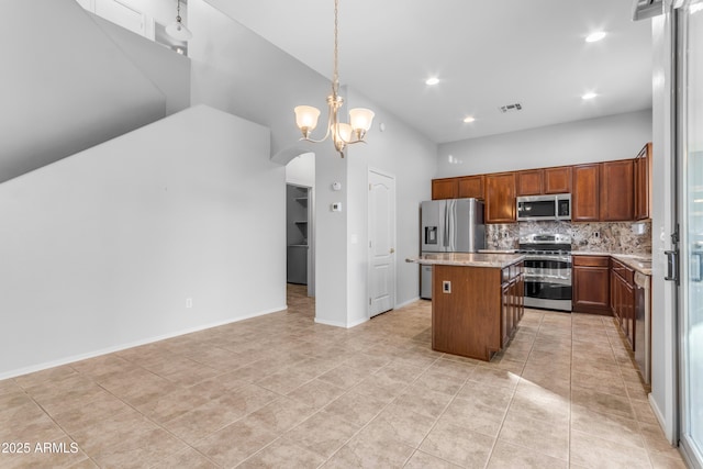 kitchen with pendant lighting, backsplash, a kitchen island, a chandelier, and stainless steel appliances