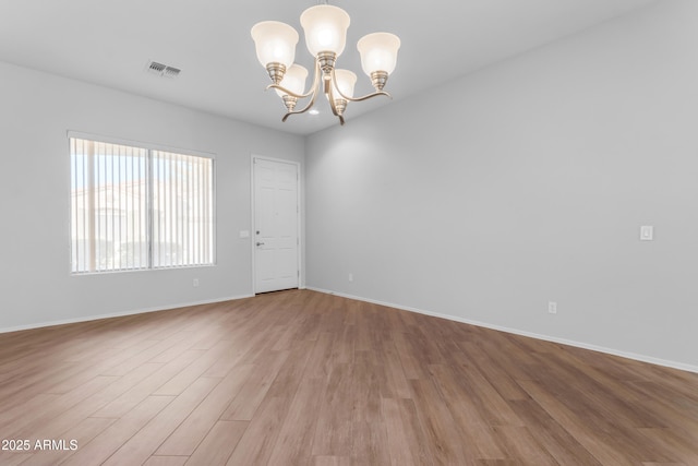 empty room featuring hardwood / wood-style floors and a chandelier