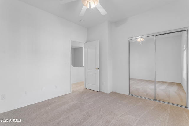 unfurnished bedroom featuring ceiling fan, a closet, and light carpet