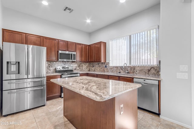 kitchen with appliances with stainless steel finishes, a kitchen island, decorative backsplash, sink, and light tile patterned floors