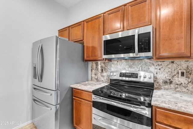 kitchen featuring decorative backsplash, light stone countertops, and stainless steel appliances