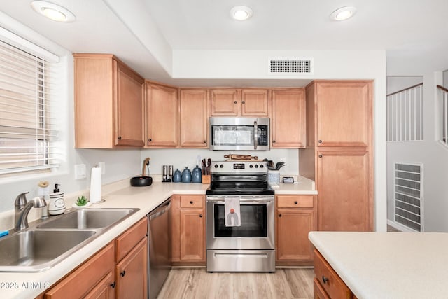 kitchen with appliances with stainless steel finishes, sink, and light wood-type flooring