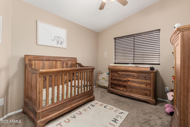 bedroom with vaulted ceiling, a nursery area, ceiling fan, and carpet