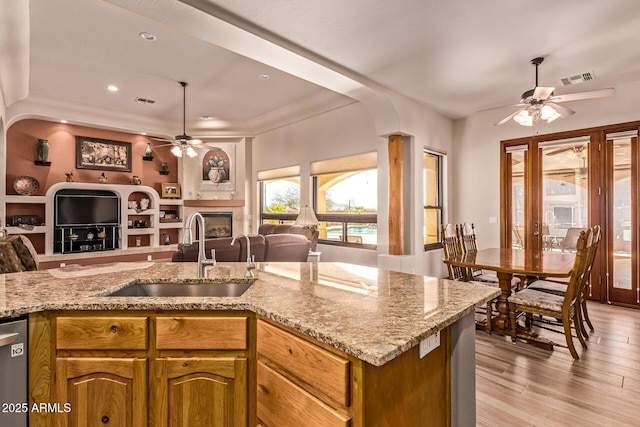 kitchen featuring a sink, a ceiling fan, a fireplace, open floor plan, and visible vents