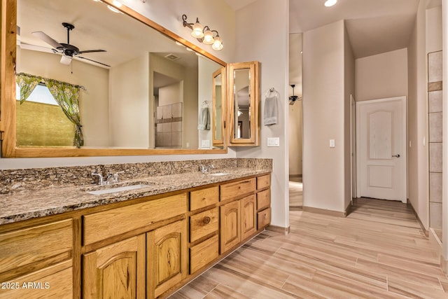 full bathroom featuring double vanity, wood finished floors, a sink, and a ceiling fan