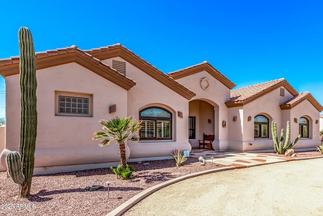 mediterranean / spanish-style house featuring stucco siding and a tile roof