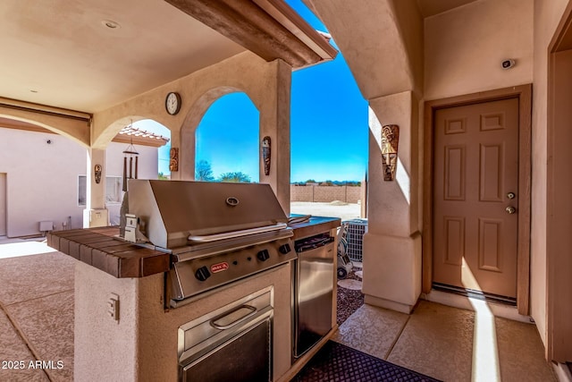 view of patio featuring central AC unit, exterior kitchen, and area for grilling