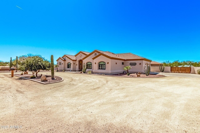 rear view of house with fence, driveway, stucco siding, and a tiled roof