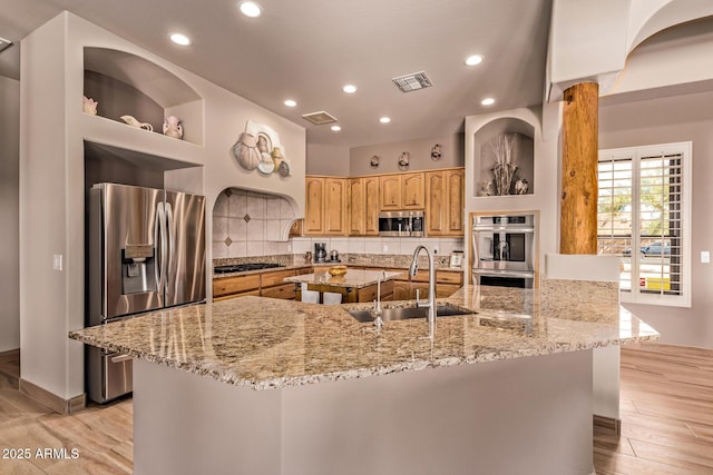 kitchen with tasteful backsplash, stainless steel appliances, a spacious island, a sink, and visible vents