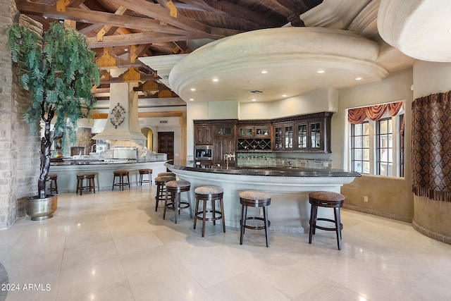 kitchen featuring wood ceiling, tasteful backsplash, beam ceiling, light tile patterned flooring, and dark brown cabinets