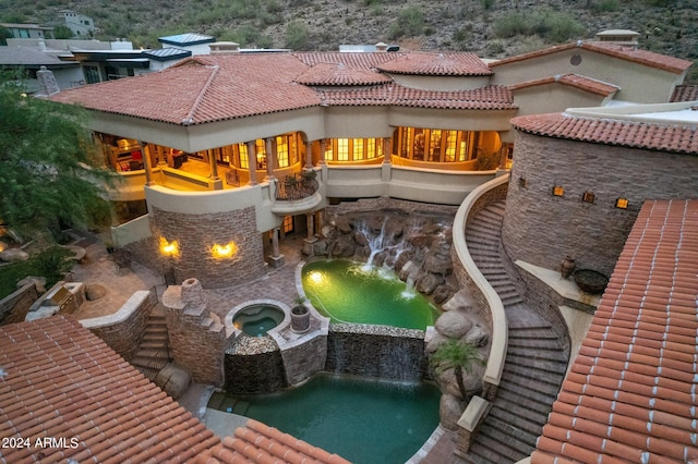 back of house featuring a tiled roof and an in ground hot tub