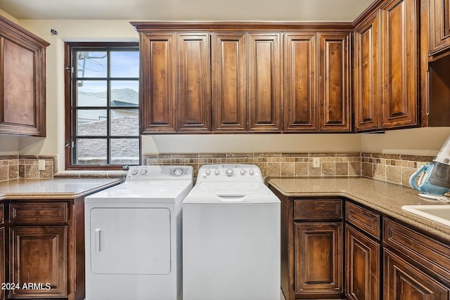 washroom with washer and dryer and cabinets