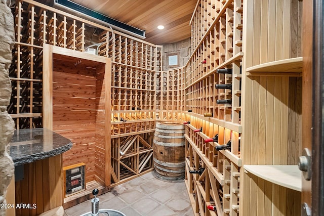 wine room featuring tile patterned flooring, wood walls, and wooden ceiling