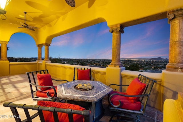 patio terrace at dusk featuring ceiling fan and a fire pit