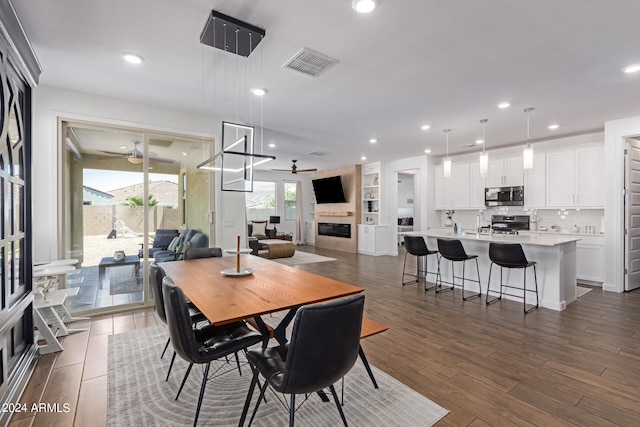 dining space with ceiling fan, sink, built in features, and dark wood-type flooring