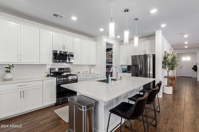 kitchen featuring white cabinets, sink, a kitchen island with sink, appliances with stainless steel finishes, and dark hardwood / wood-style flooring