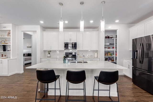 kitchen with an island with sink, stainless steel appliances, white cabinetry, and dark hardwood / wood-style flooring