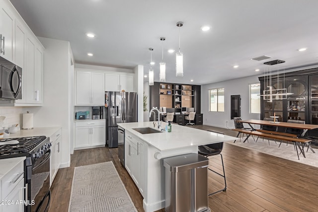 kitchen featuring pendant lighting, a kitchen island with sink, dark wood-type flooring, white cabinetry, and black appliances