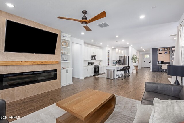 living room featuring built in features, ceiling fan, sink, and dark hardwood / wood-style flooring