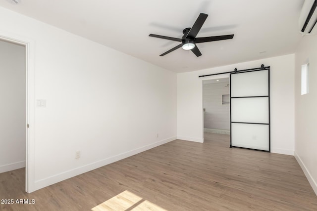 1338 E Granada Rd, Phoenix, AZ 85006 - spare room with a wall mounted AC, a ceiling fan, a barn door, and light wood-style floors