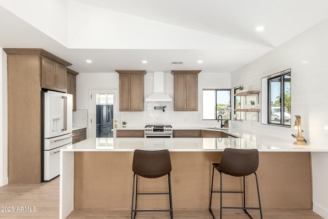 1338 E Granada Rd, Phoenix, AZ 85006 - kitchen featuring wall chimney range hood, white refrigerator with ice dispenser, gas stove, freestanding refrigerator, and a peninsula