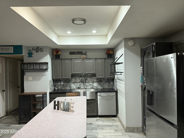 kitchen with gray cabinets, stainless steel appliances, visible vents, and light wood-style floors