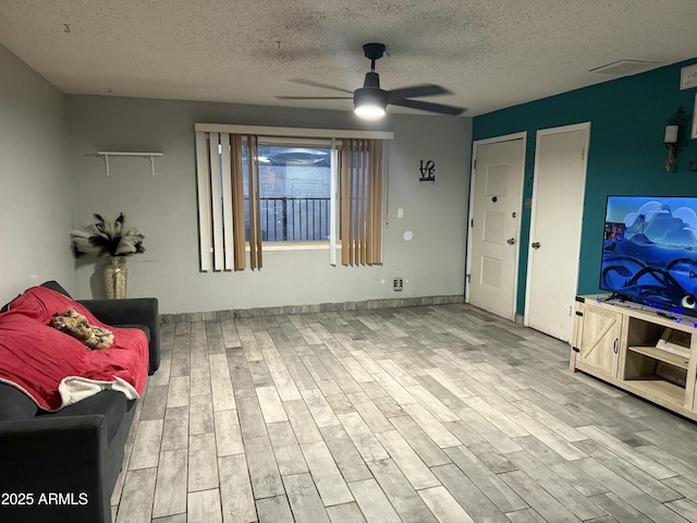 living room with a textured ceiling, wood finished floors, and a ceiling fan