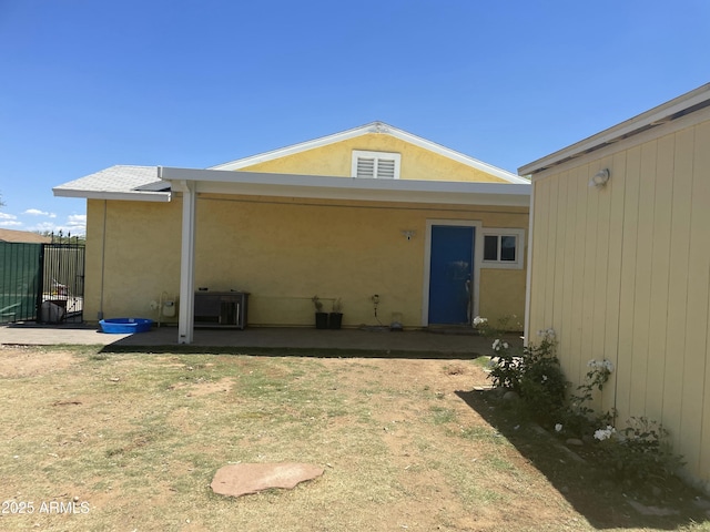 back of property with a lawn, a patio, stucco siding, and fence