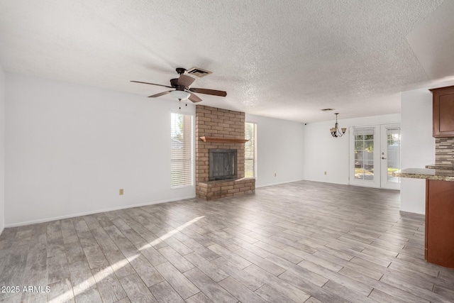 unfurnished living room featuring a brick fireplace, a textured ceiling, light hardwood / wood-style flooring, and ceiling fan