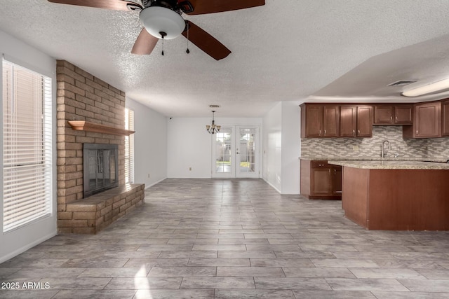 kitchen featuring sink, hanging light fixtures, a brick fireplace, ceiling fan, and backsplash