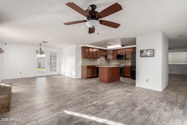 kitchen featuring decorative light fixtures, light hardwood / wood-style flooring, appliances with stainless steel finishes, a kitchen island, and decorative backsplash