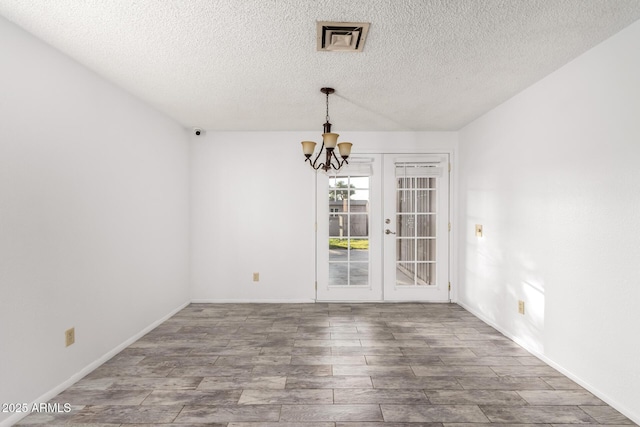 unfurnished room featuring hardwood / wood-style flooring, a textured ceiling, french doors, and a chandelier