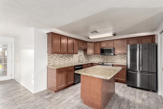 kitchen featuring a kitchen island, sink, decorative backsplash, stainless steel appliances, and a textured ceiling