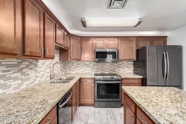 kitchen featuring stainless steel appliances, light stone countertops, sink, and backsplash