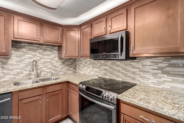 kitchen with appliances with stainless steel finishes, light stone countertops, sink, and backsplash