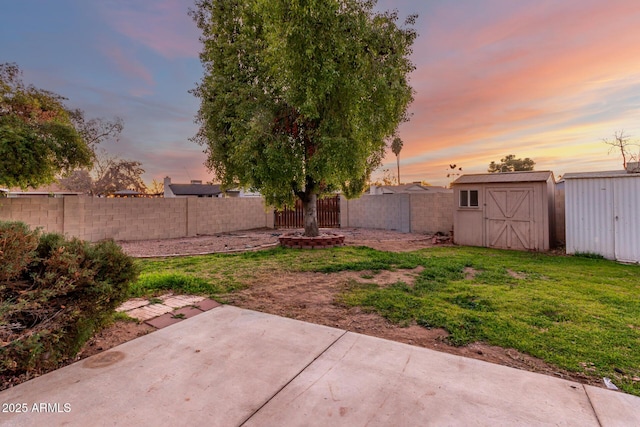 yard at dusk featuring a storage shed and a patio area