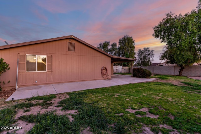 back house at dusk with a yard and a patio area