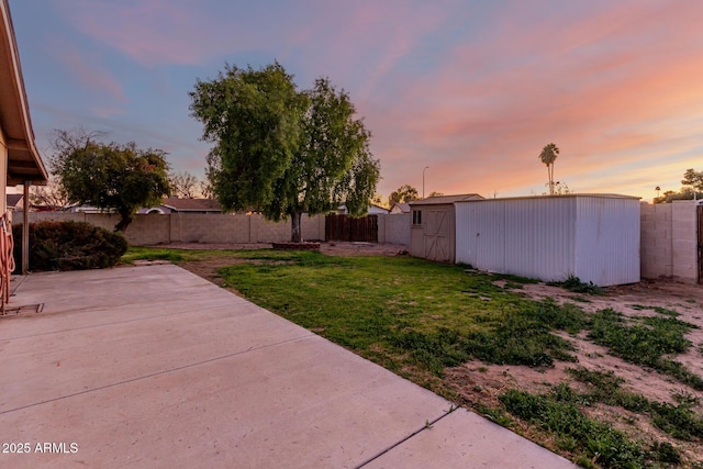 yard at dusk with a patio and a storage shed