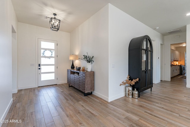 entrance foyer with light hardwood / wood-style floors and a chandelier