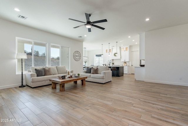 living room with sink, ceiling fan, and light wood-type flooring